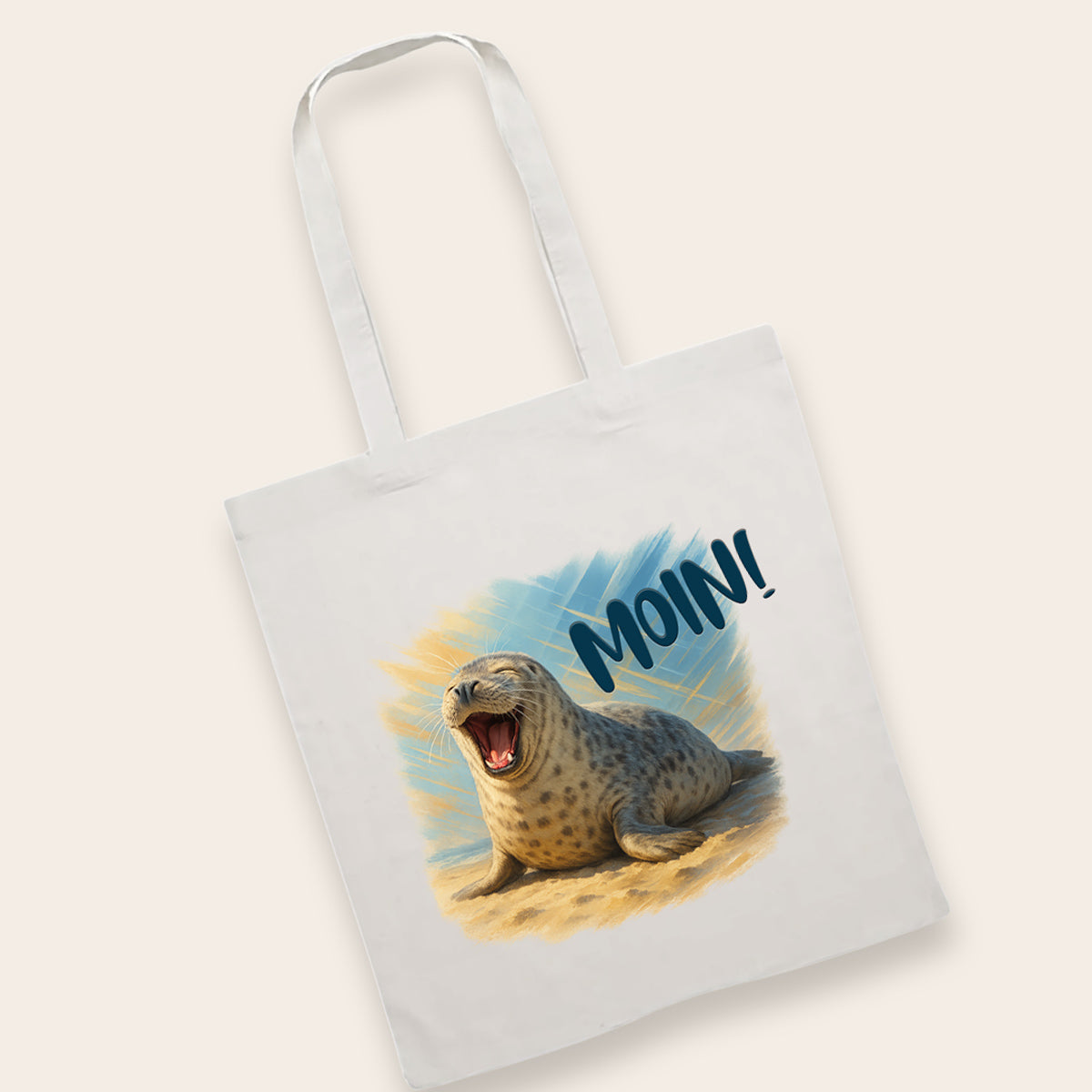 Weiße Baumwolltasche mit einem detailreichen Druck einer lachenden Robbe im Sand.