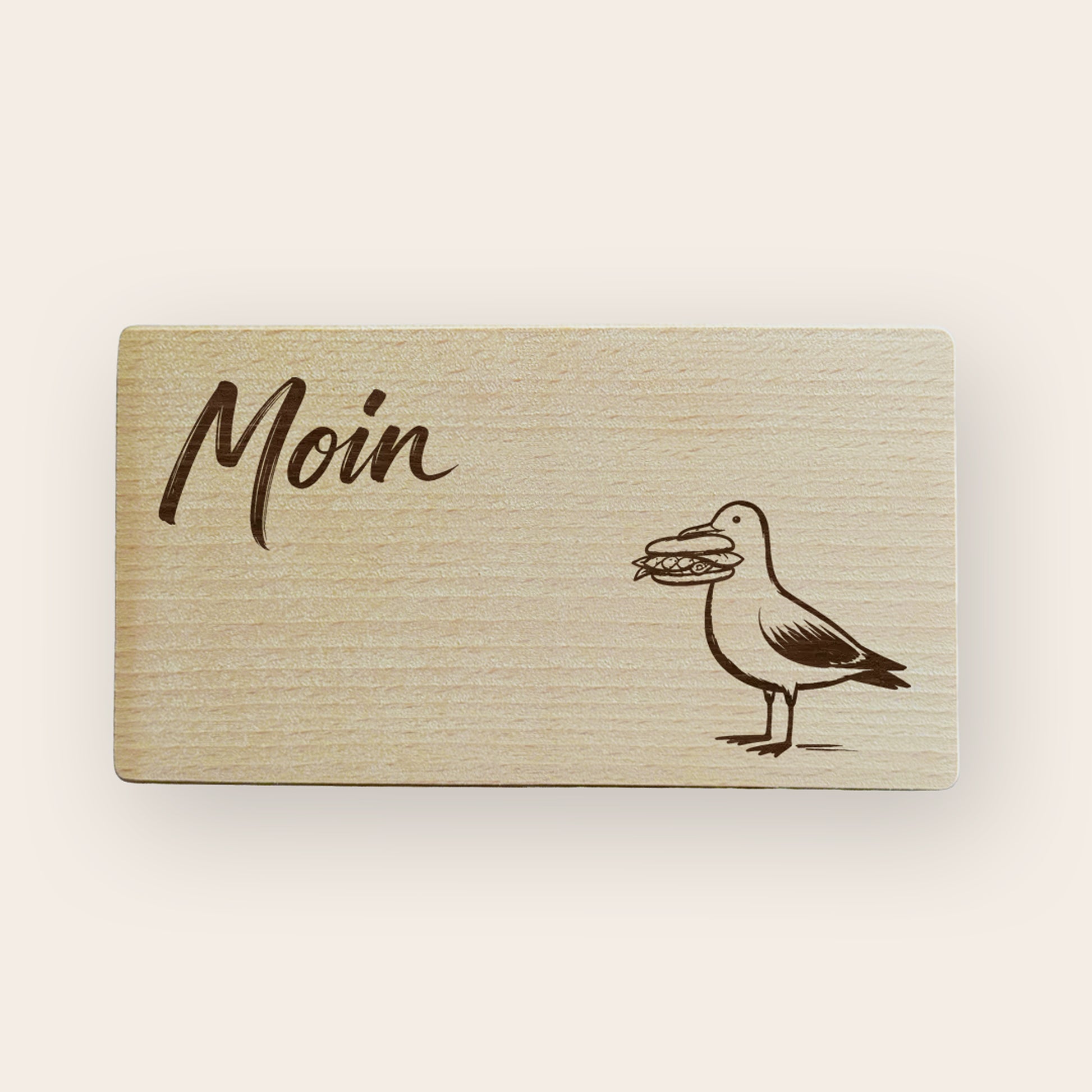 Holzbrettchen mit gravierter Möwe, die ein Fischbrötchen im Schnabel hält und dem Schriftzug Moin 