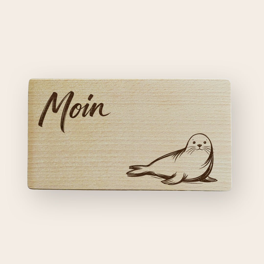 Holzbrettchen mit Lasergravur einer liegenden Robbe im maritimen Design.
