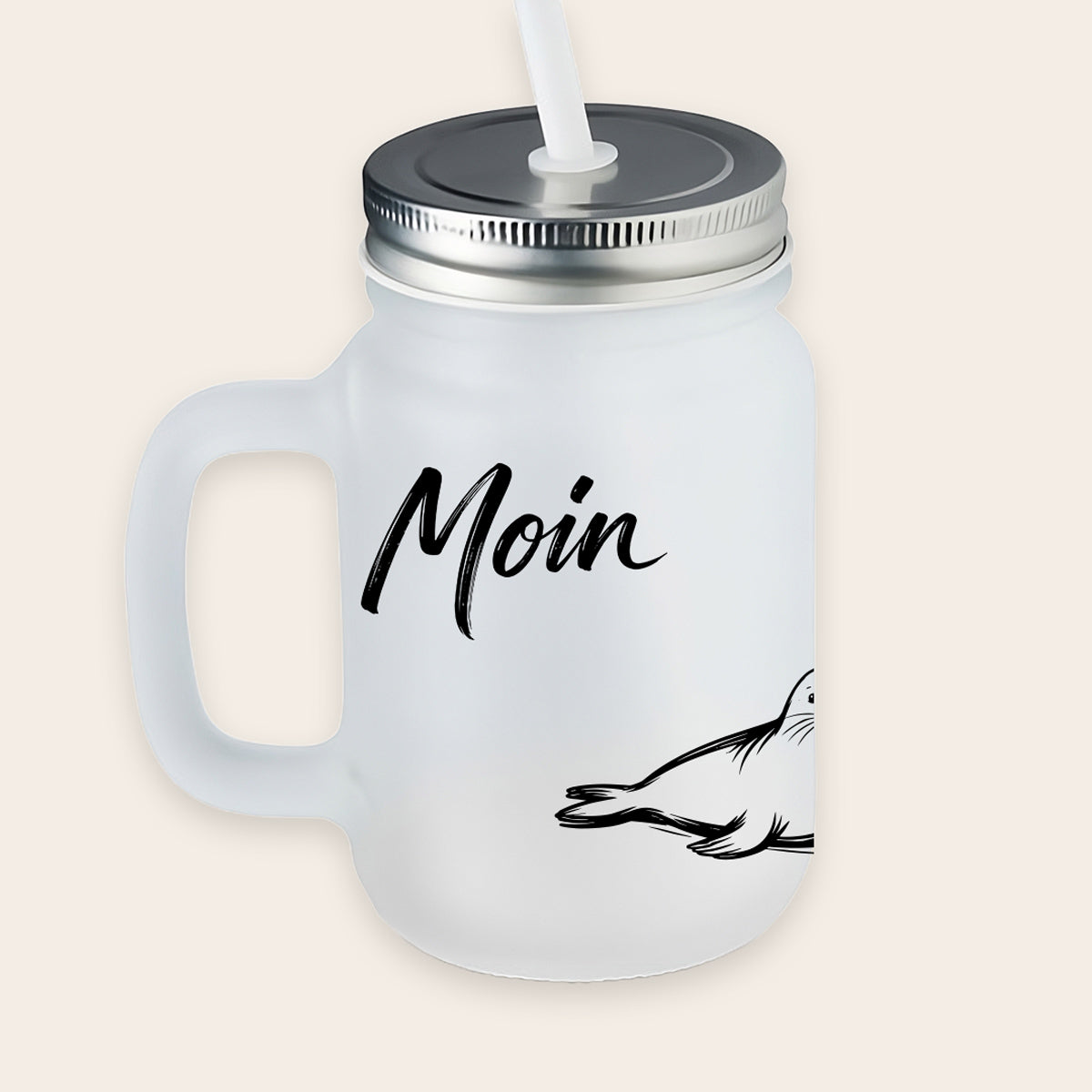Satiniertes, matt-weißes Trinkglas mit Henkel, Metalldeckel und weißem Strohhalm, bedruckt mit einer liegenden, aufmerksam blickenden Robbe und dem Schriftzug „Moin“.