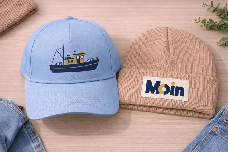 Hellblaue Cap mit Fischkutter-Motiv und Beanie mit MOIN-Patch als Kollektionsbild für Accessoires im Shop von Dein Printwerk